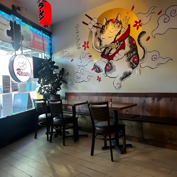Three Bowls Ramen interior with a large mural of a cat eating ramen, wooden tables, and chairs.